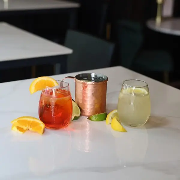 An Aperol spritz, a Moscow mule and a lemon cocktail on a marble table