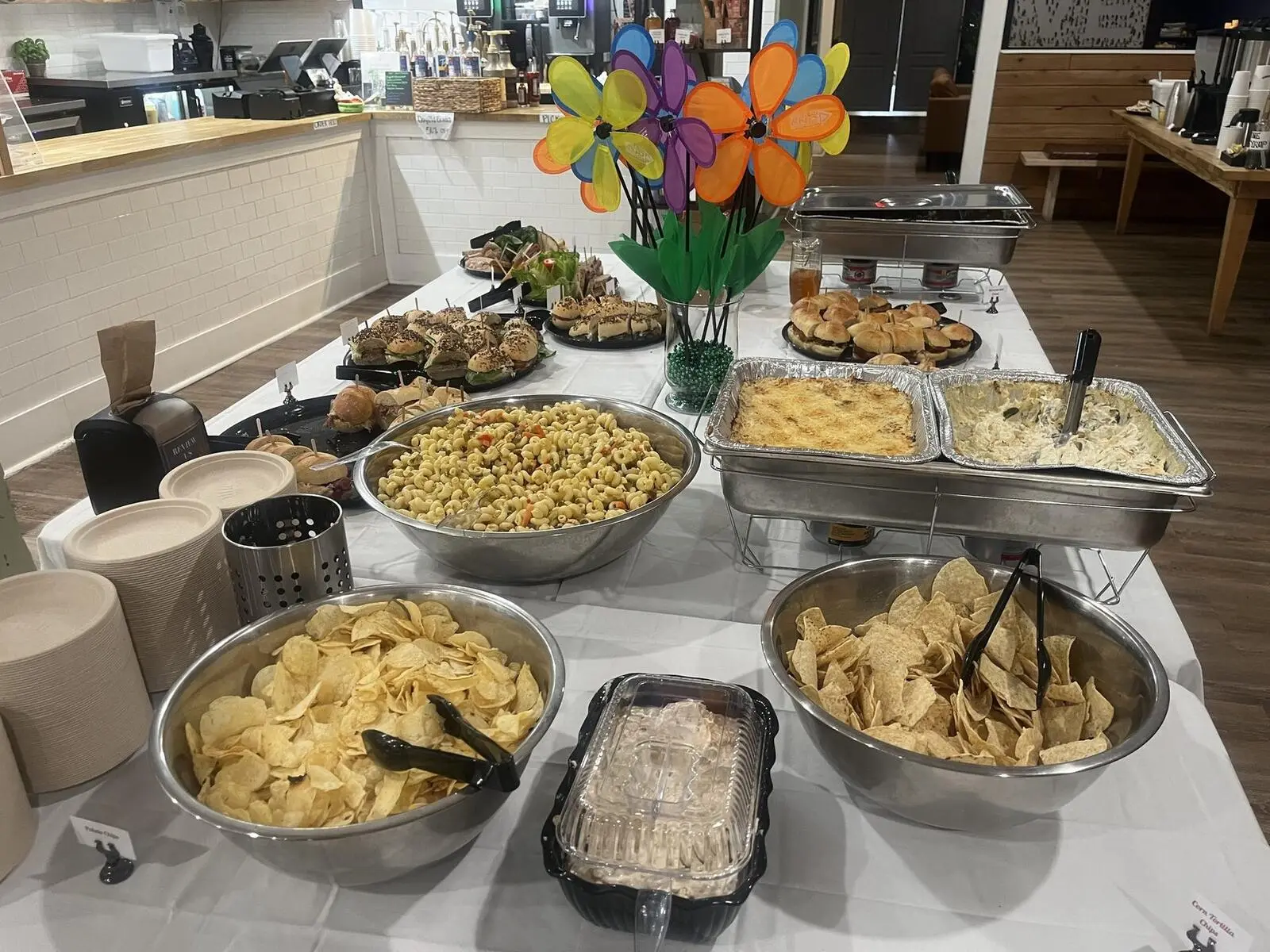 A group buffet set up in the dining room: pasta salad, chafing dishes, chips and sandwiches