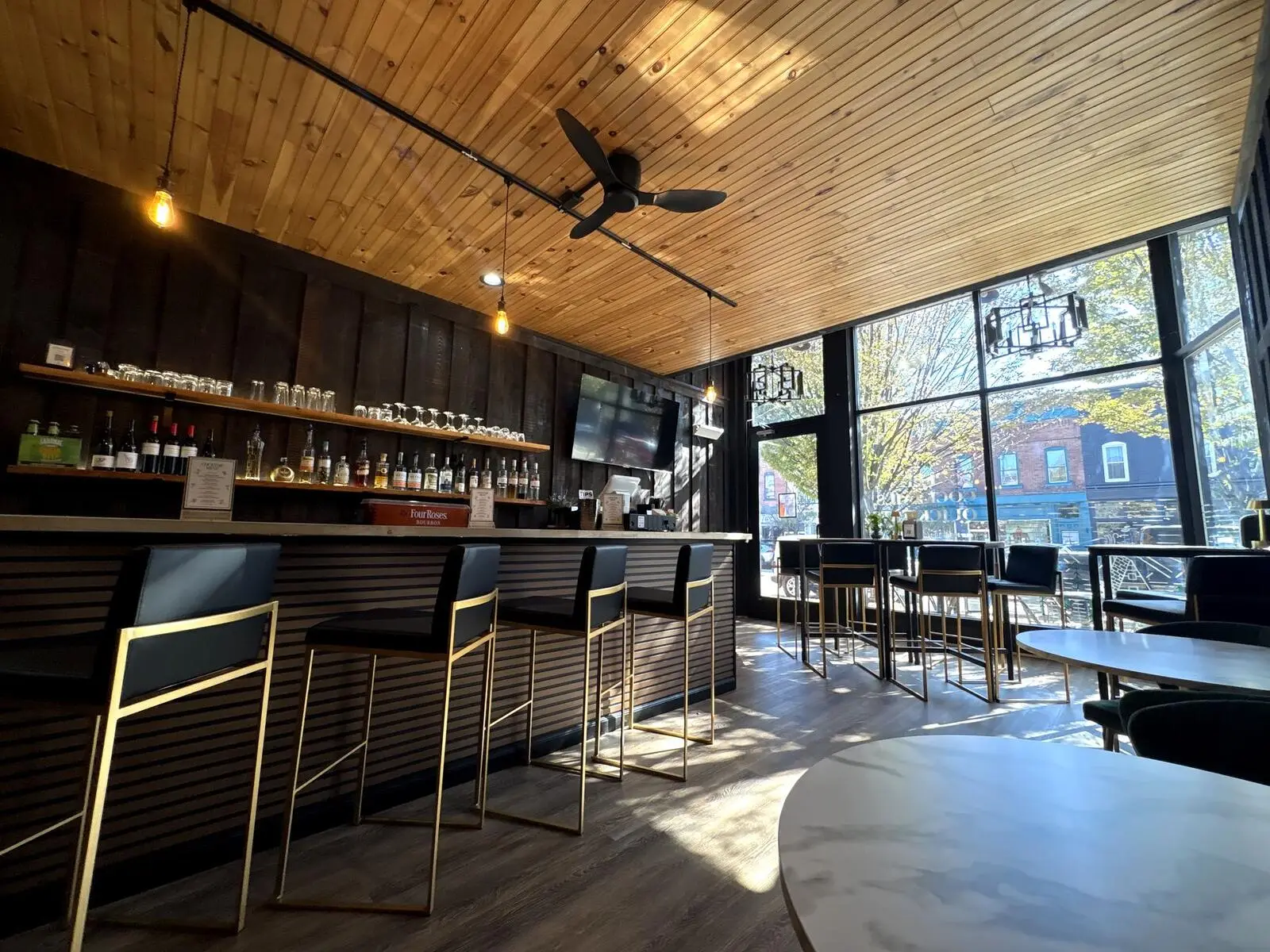 The Last Chair bar, with a wood ceiling, gold bar stools and big windows onto Washington Street