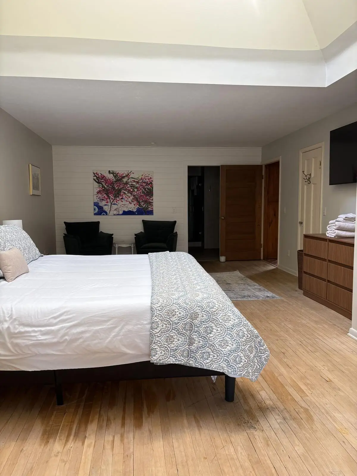 A bedroom with a king bed and two armchairs