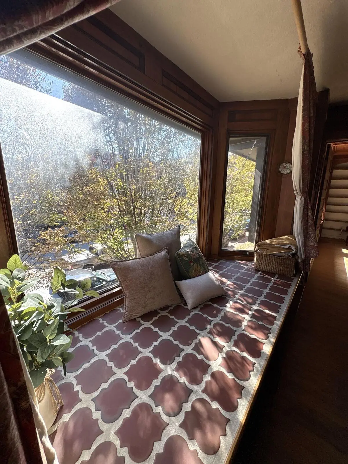 A window seat with cushions looking out over autumn trees