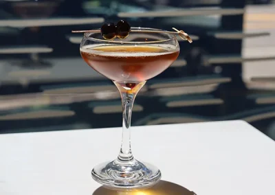 Cocktail in a coupe glass garnished with a cherry