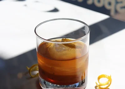 Cocktail served over a large ice cube with a citrus twist