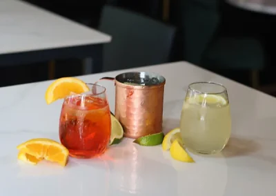 Cocktails and a copper mug on a table with citrus garnishes