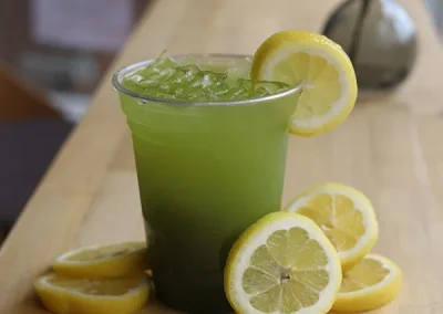 Green lemonade served over ice with fresh lemon slices