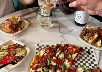 Guests toasting wine glasses over a table of flatbreads and shared plates